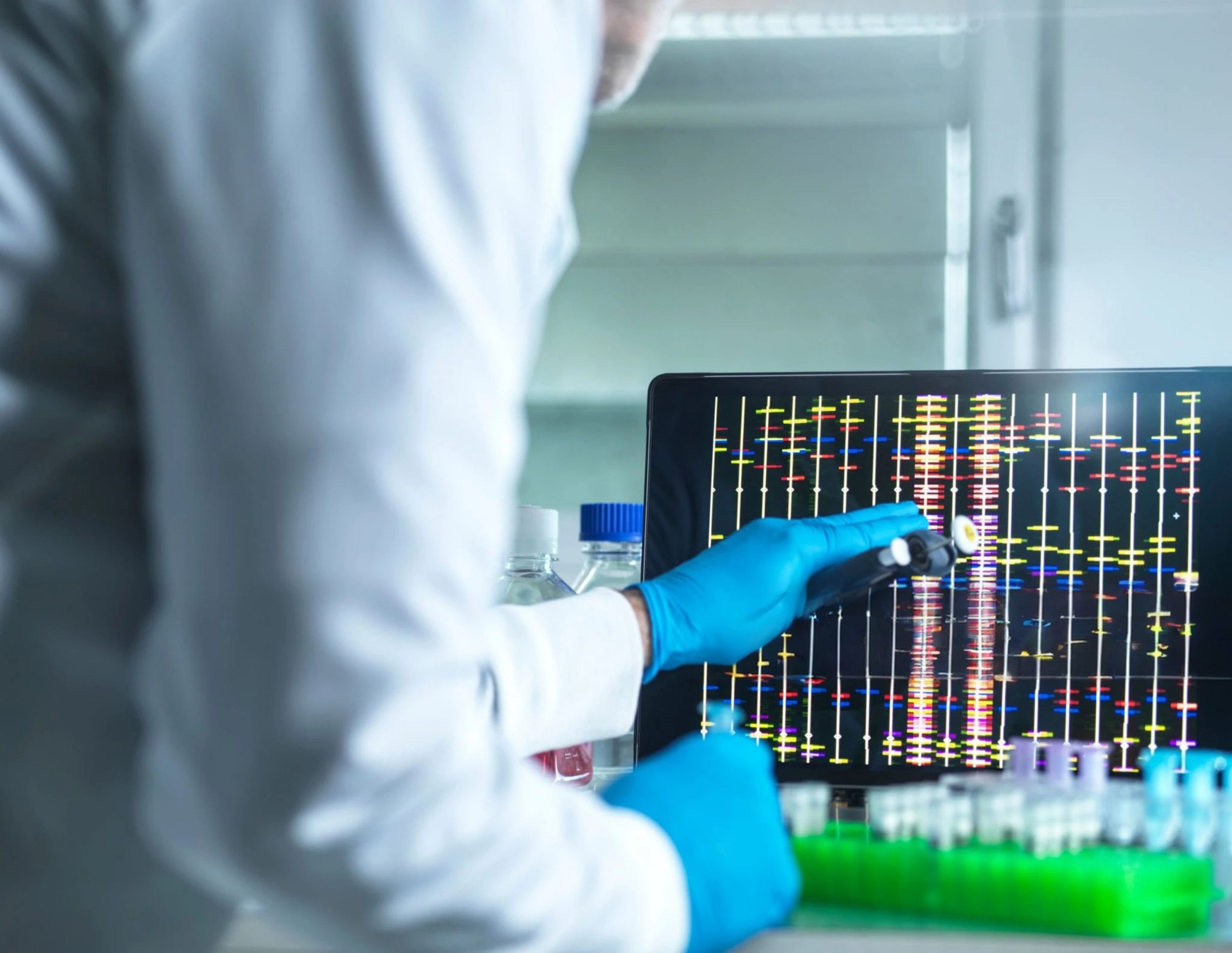 A laboratory scene features a laptop displaying a dna sequencing analysis in a bright, modern environment.